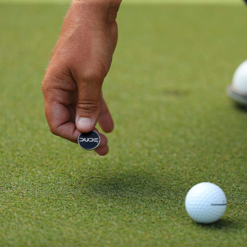 Hand placing the Magnetic Ball Marker next to a golf ball